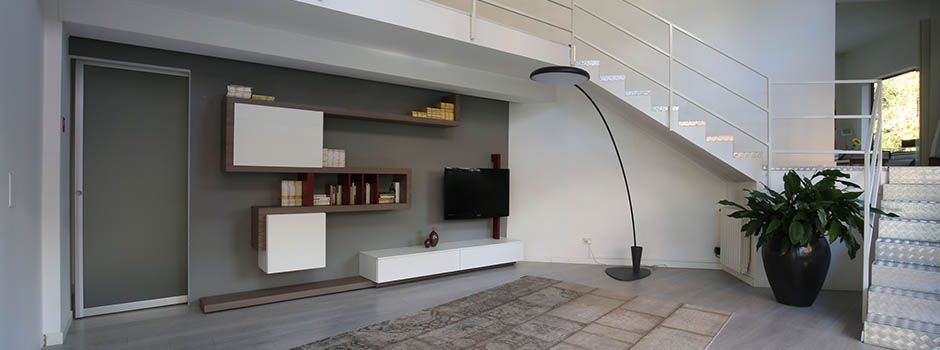Angolo dello showroom con parete attrezzata, lampada ad arco e scala